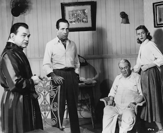 Pictured, left to right: Edward G. Robinson, Humphrey Bogart, Lionel Barrymore and Lauren Bacall in a scene from the 1948 noir film Key Largo, directed by John Huston. Photo courtesy of FPG/Hulton Archive/Getty Images.